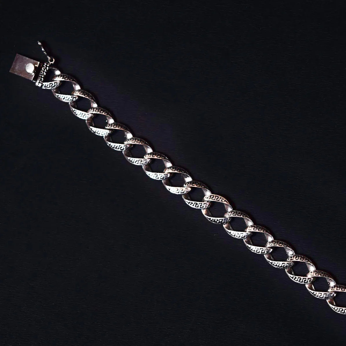 silver chain bracelet with engraved Greek key pattern on black background