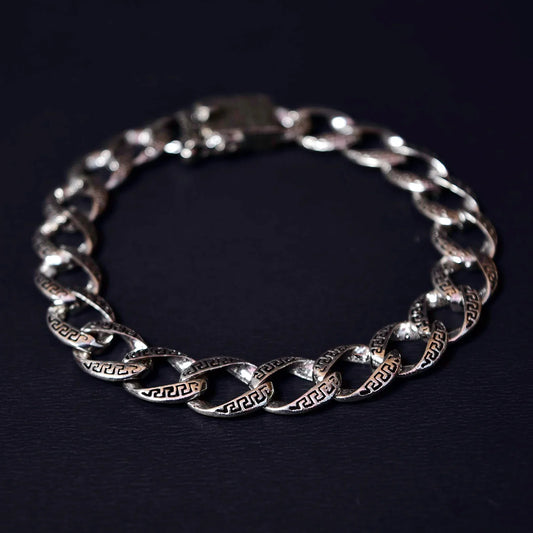 Silver chain bracelet with Greek key pattern links on dark background