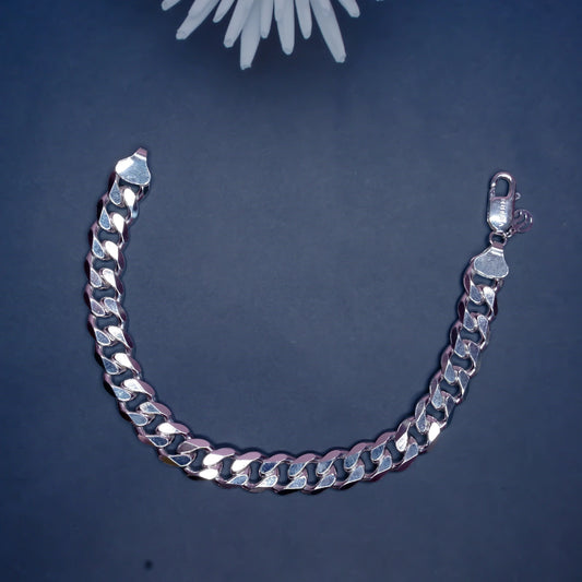 Silver Cuban link chain bracelet on dark background with white flower decoration