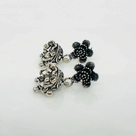 Close-up of oxidized silver jhumka earrings with intricate detailing on white background