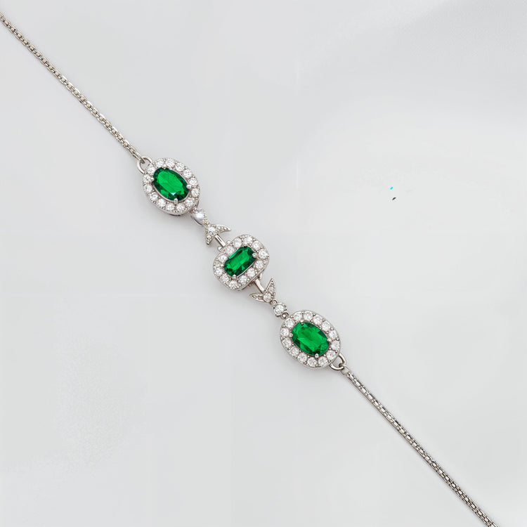 Elegant silver bracelet with pear-shaped red gemstone and diamond accents on white background