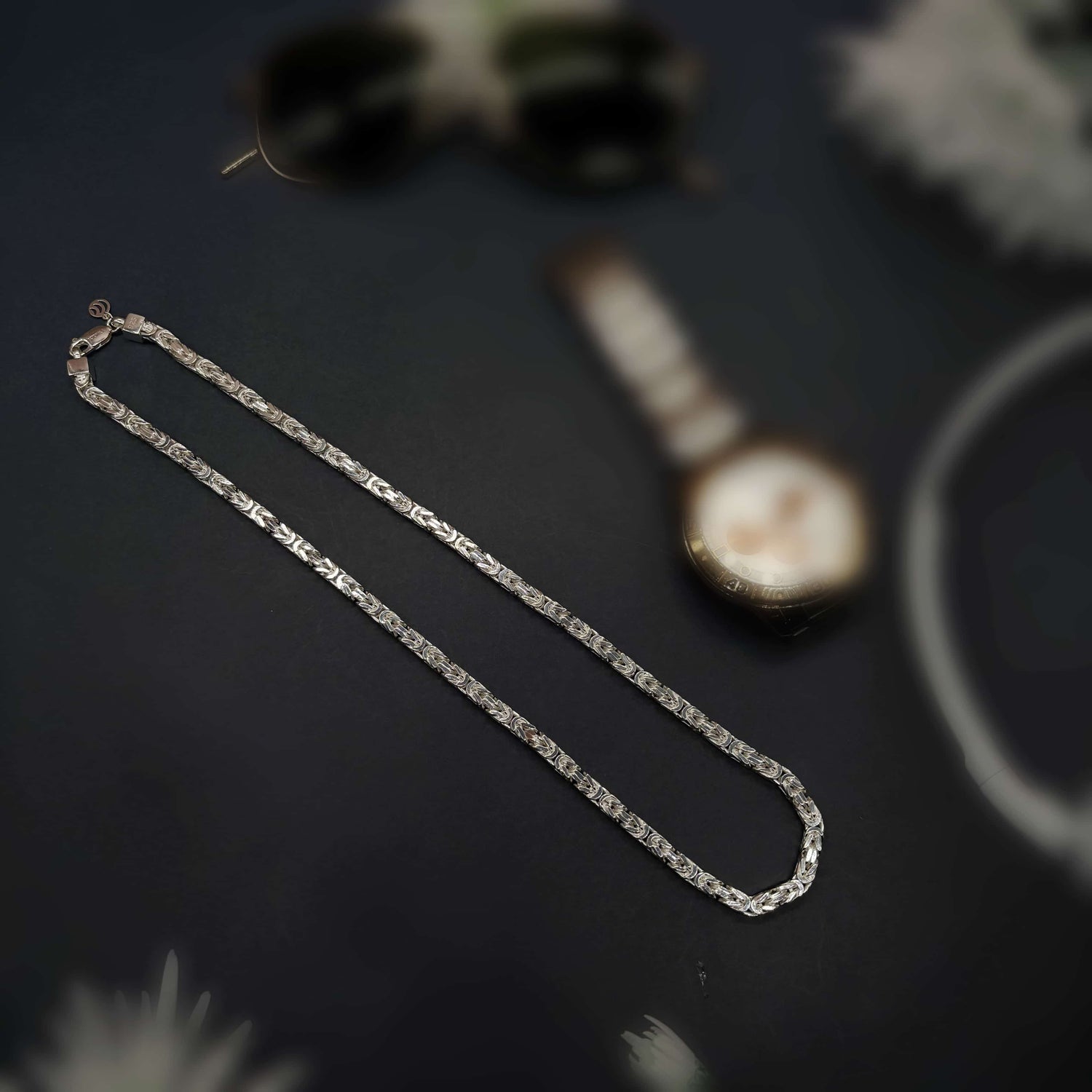 Silver chain bracelet with engraved link details on black textured background