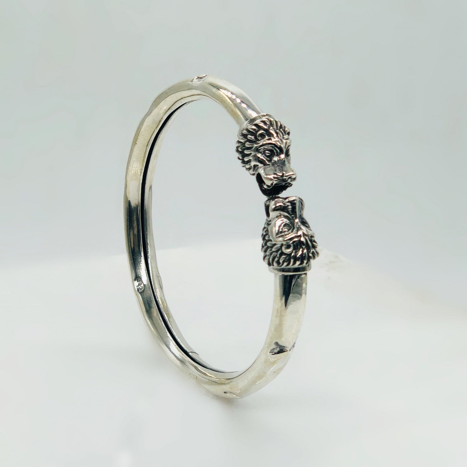 silver bracelet with intricate tribal design and a small carved brown bead on white background