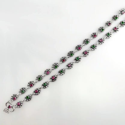 Silver anklets with alternating pink and green stones in floral settings on white background