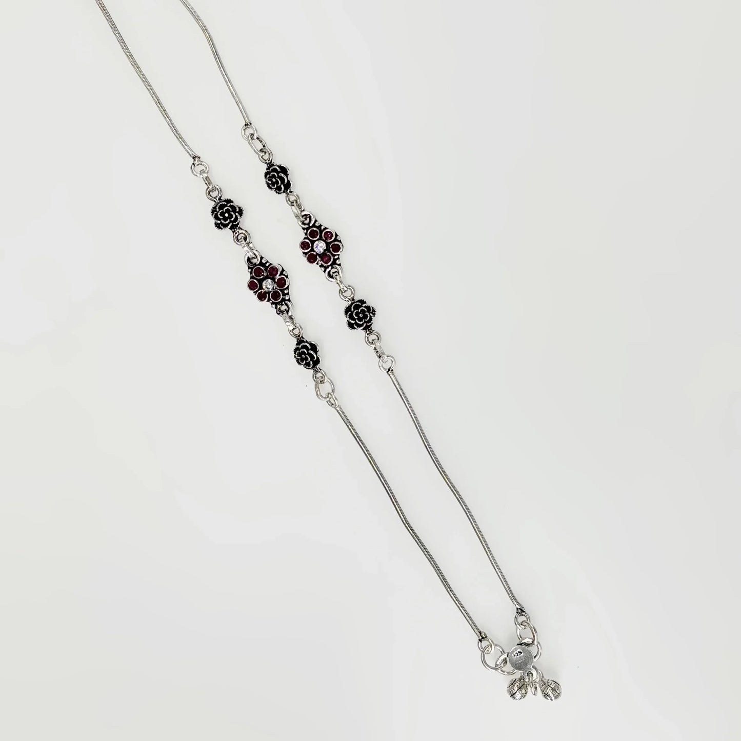 Silver necklace with floral and red gemstone accents on a white background