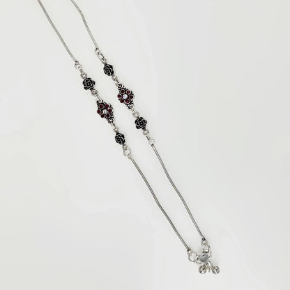 Silver necklace with floral and red gemstone accents on a white background
