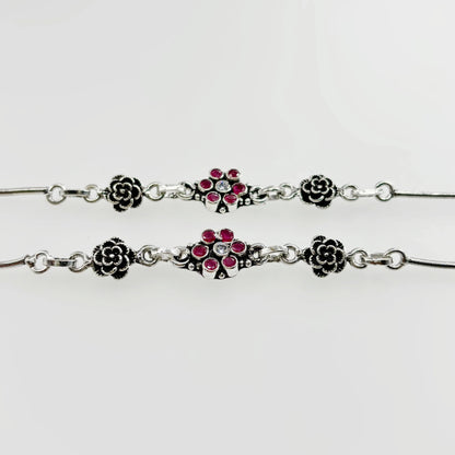 Silver anklets with floral design featuring red and clear gemstones on white background