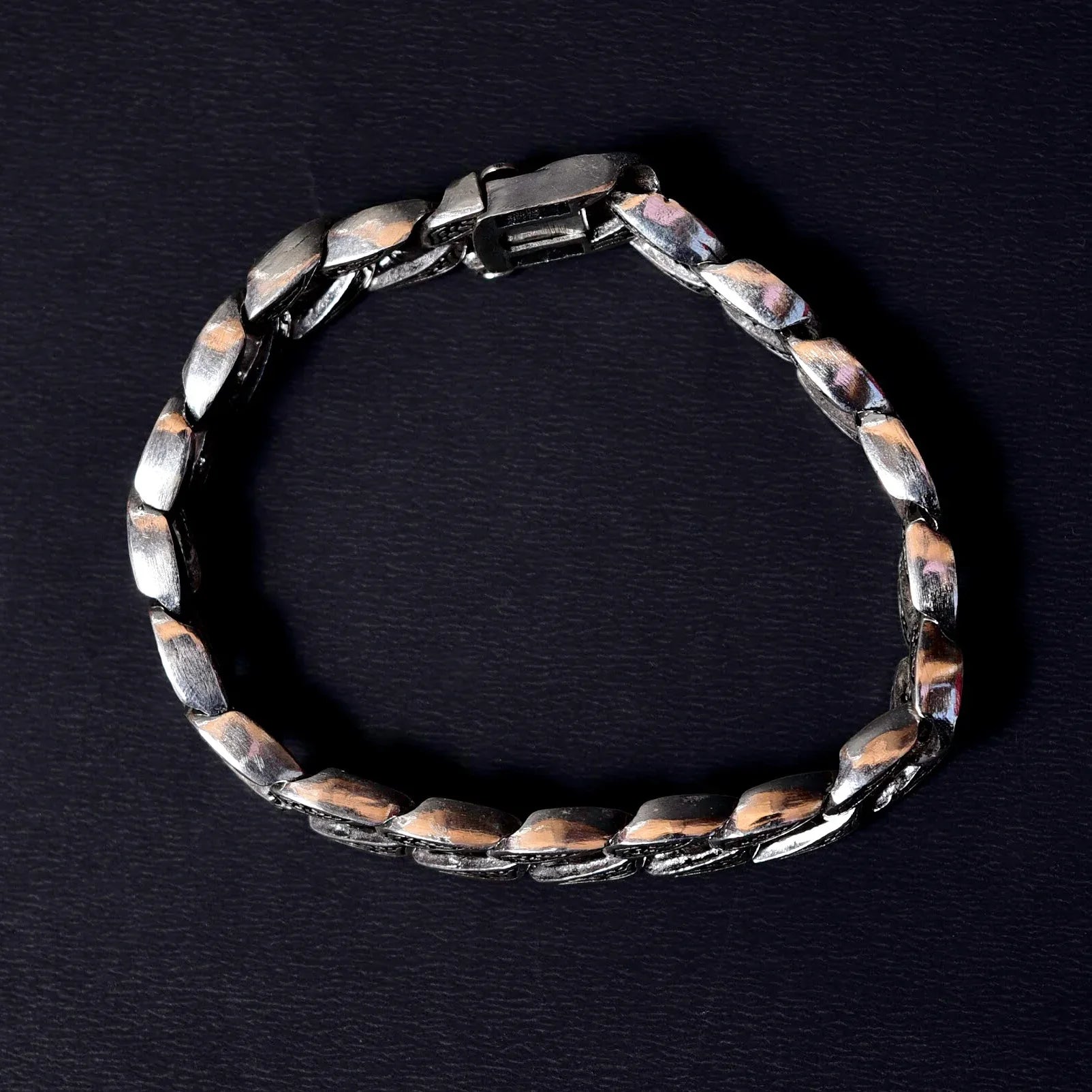 Silver link bracelet with polished rectangular links on black textured background