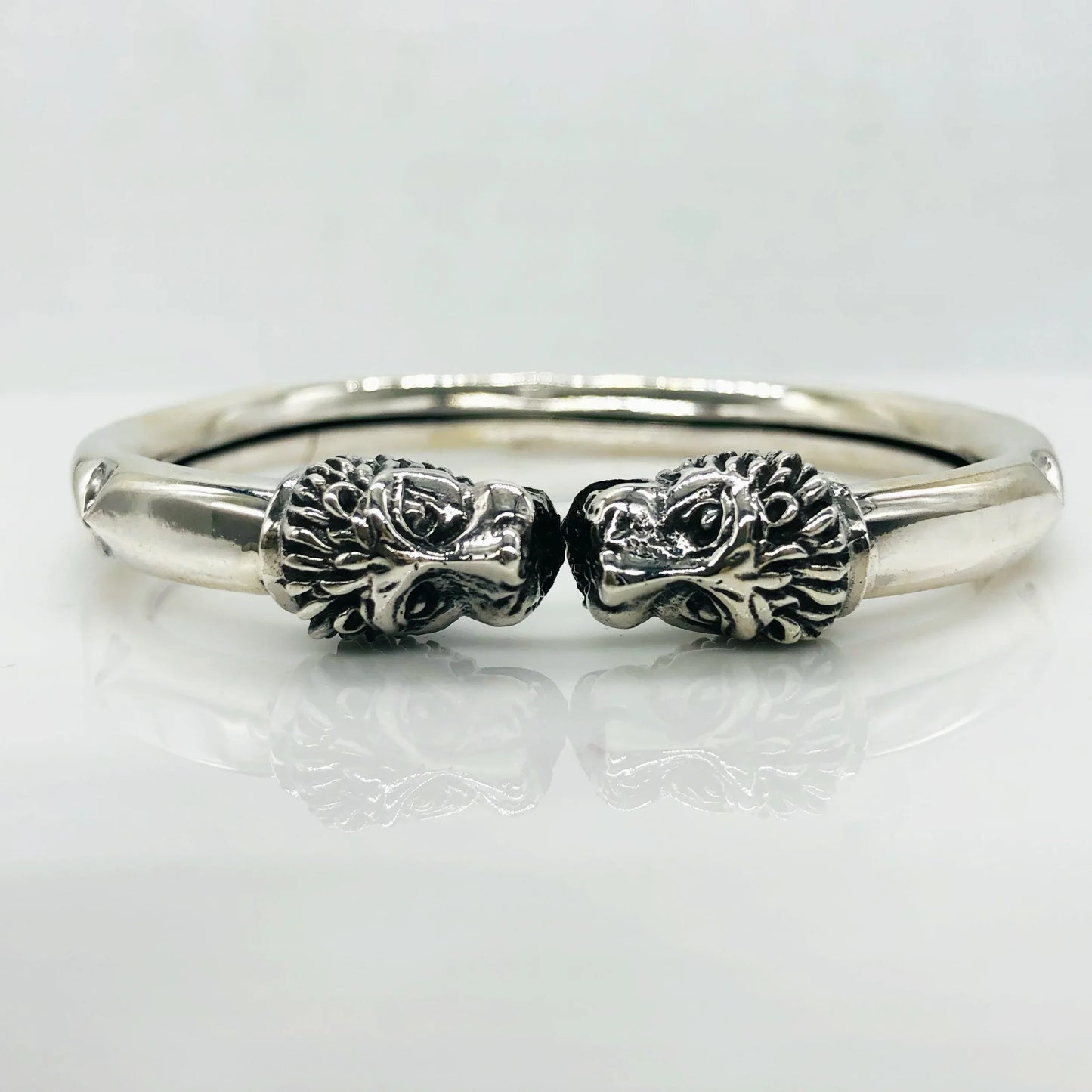 Silver bracelet featuring two intricately detailed lion head designs facing each other