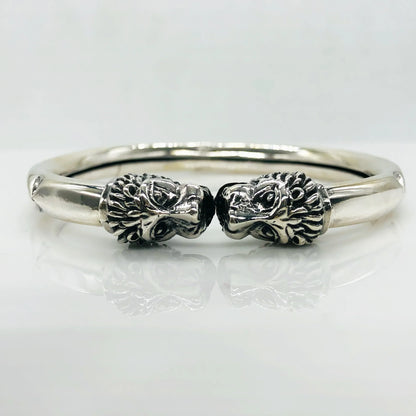Silver bracelet featuring two intricately detailed lion head designs facing each other