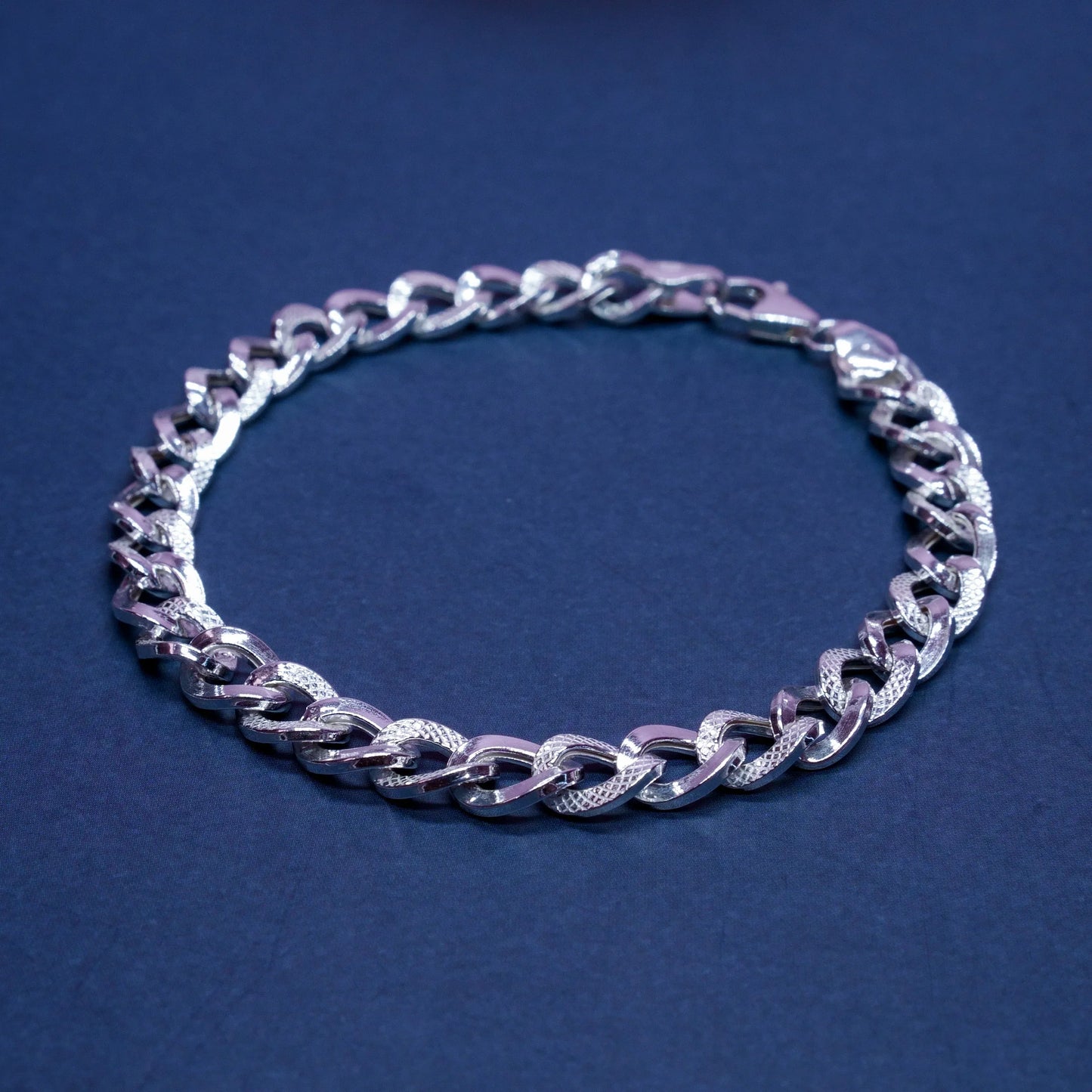 Silver textured chain bracelet on dark blue background, men's fashion jewelry