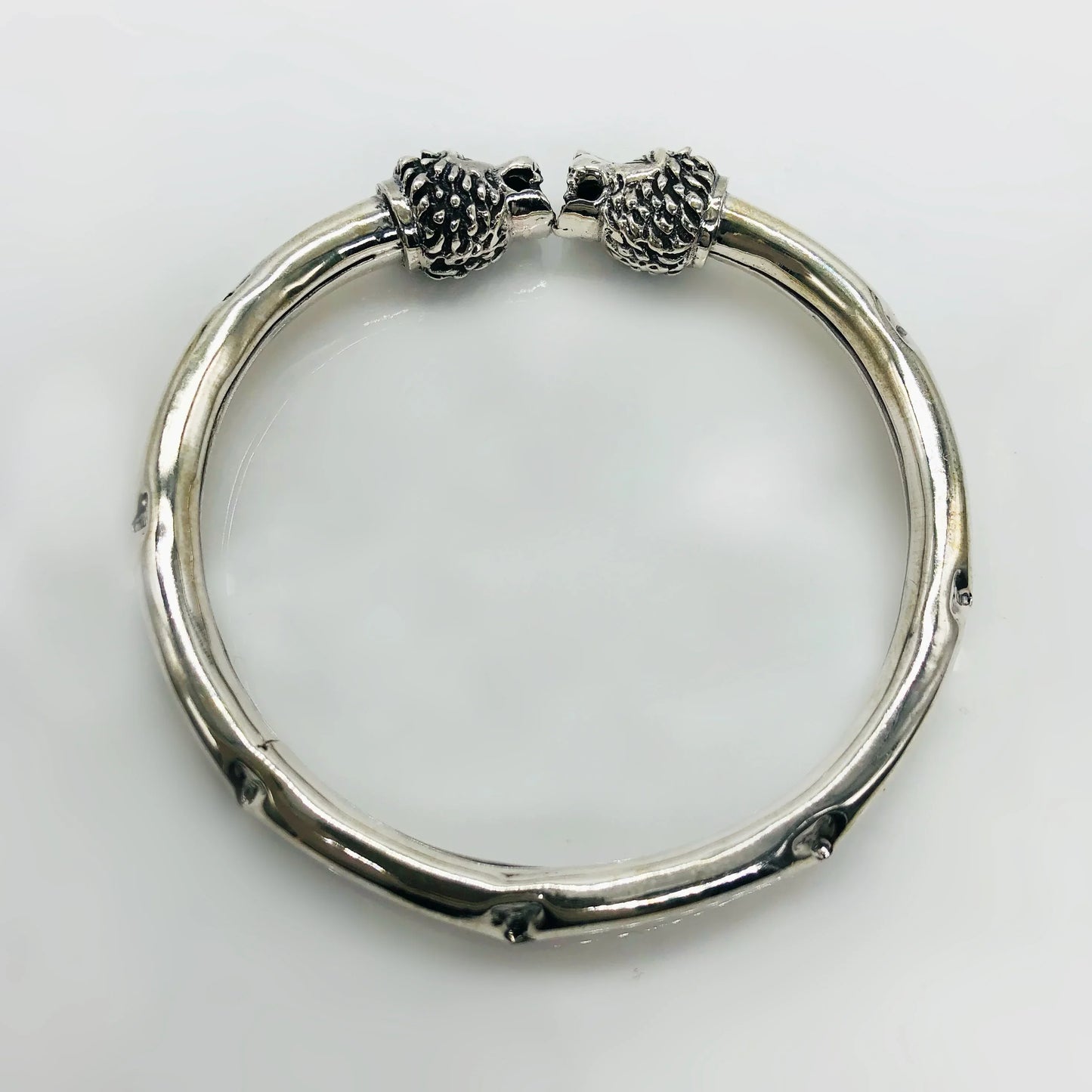 Silver bracelet with lion head ends and textured, slightly curved design