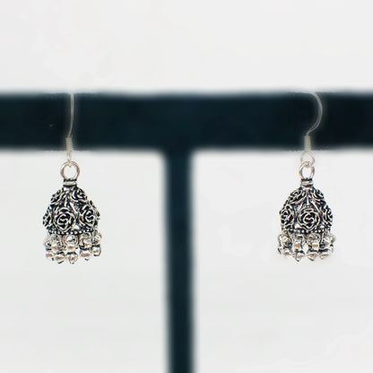 Pair of oxidized silver jhumka earrings with intricate floral design and dangling beads