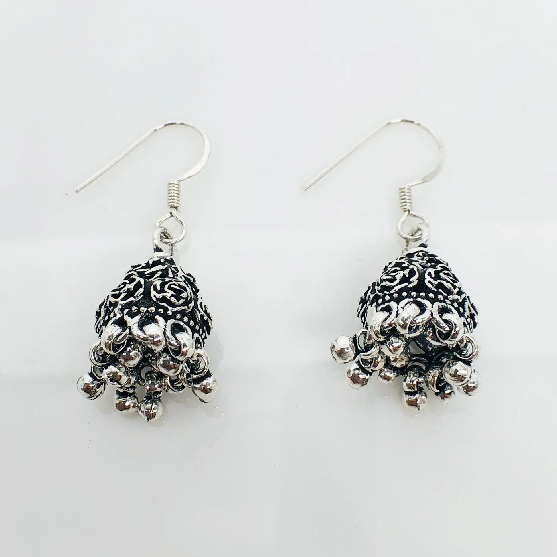 Silver oxidized jhumka earrings with intricate floral design and dangling beads