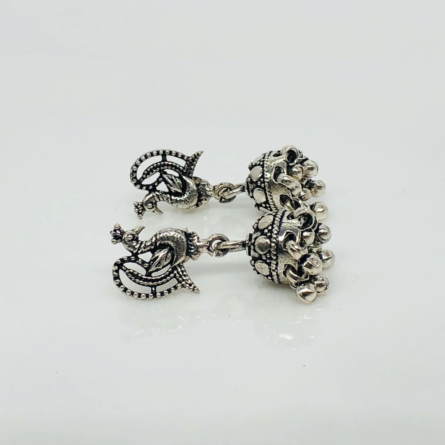 Intricate oxidized silver jhumka earrings with peacock design and dangling beads