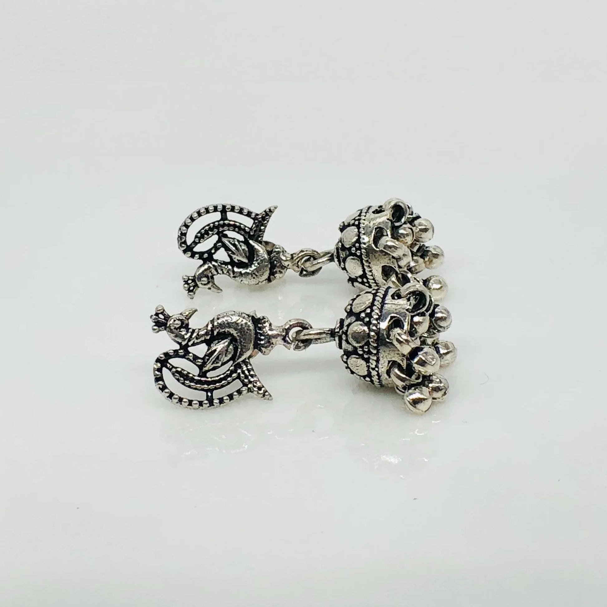Intricate oxidized silver jhumka earrings with peacock design and dangling beads