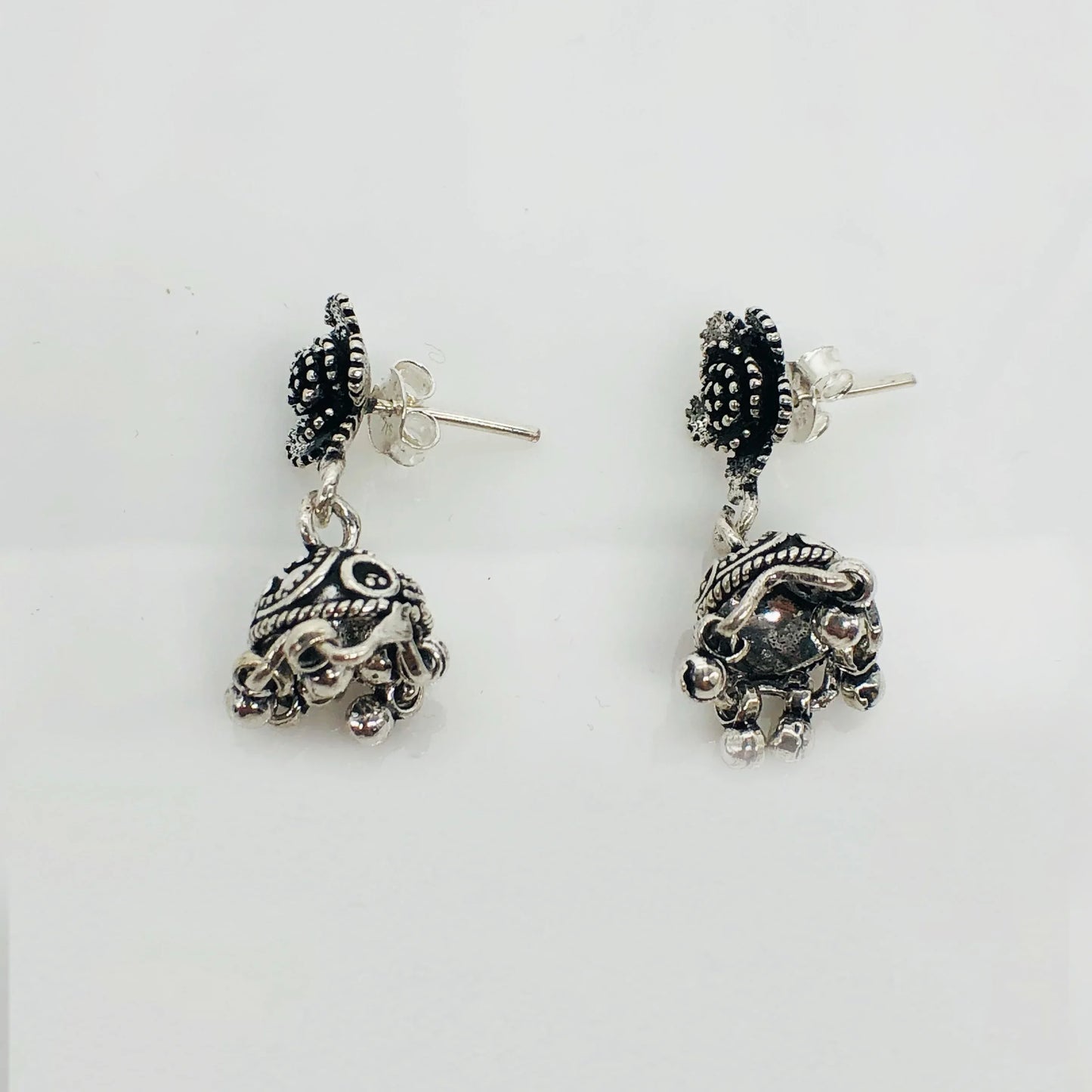 Pair of ornate silver jhumka earrings with intricate black enamel and small dangling beads
