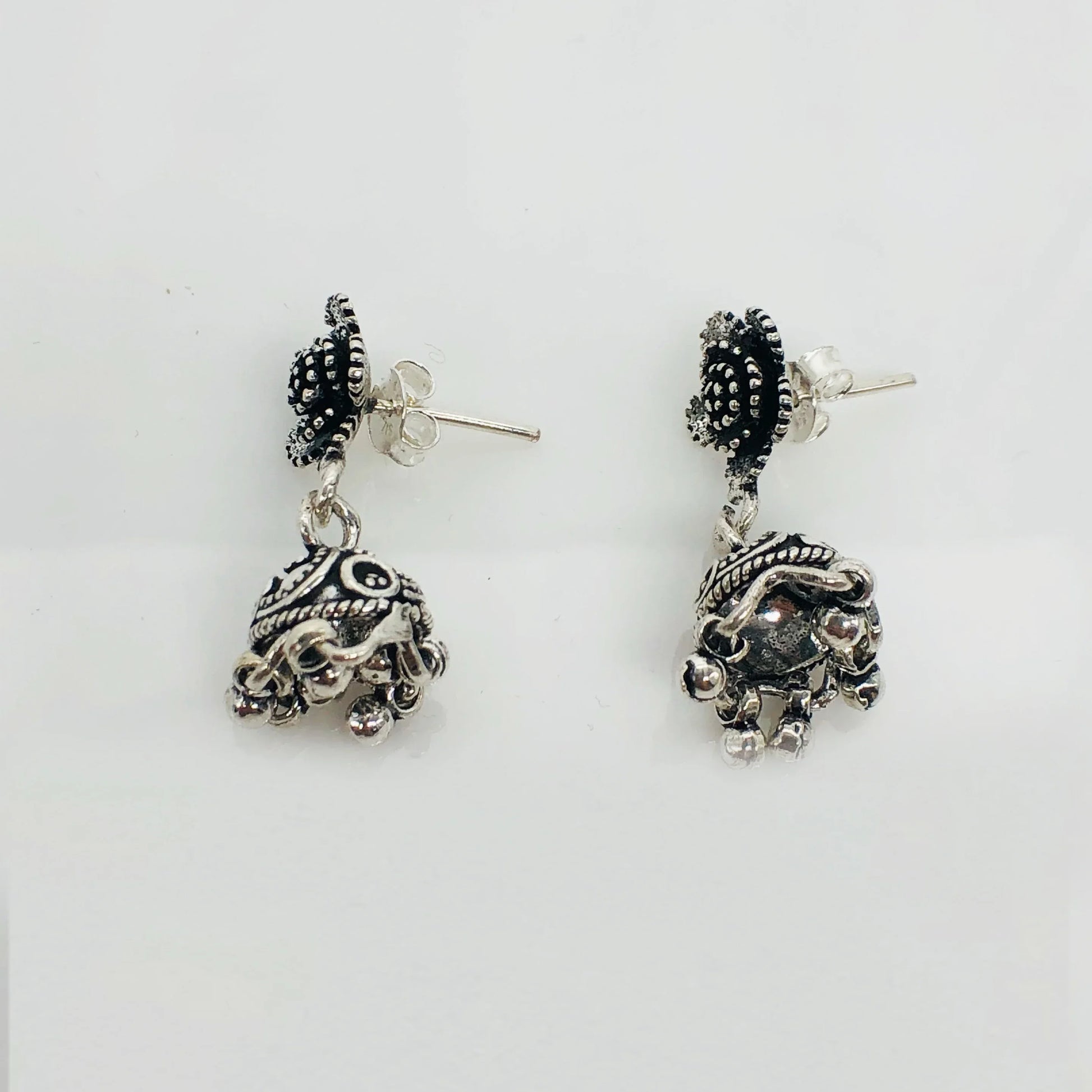 Pair of ornate silver jhumka earrings with intricate black enamel and small dangling beads