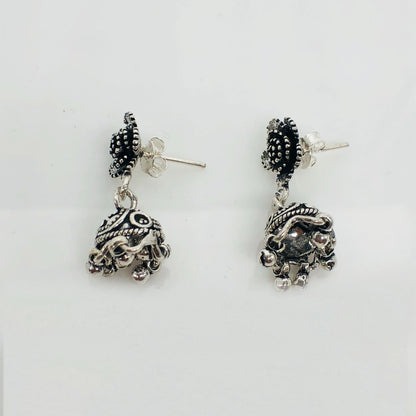 Pair of ornate silver jhumka earrings with intricate black enamel and small dangling beads